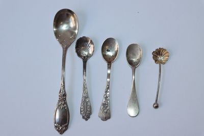 Plusieurs cuillères et cuillères à soupe sont alignées sur une surface blanche