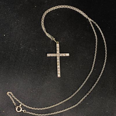 une croix en argent suspendue à une chaîne sur fond noir
