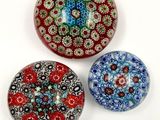three glass paperweightes with different designs on them on a white surface