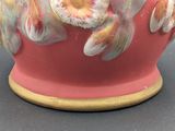 a red vase with a white and yellow design on it