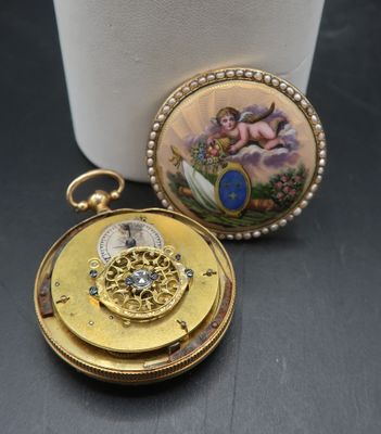 une petite montre de poche en or sur laquelle figure une image