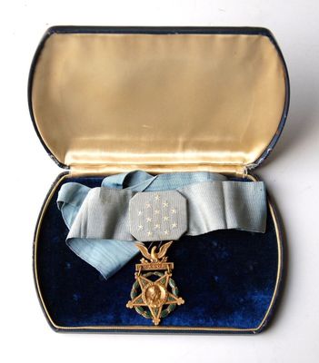 une petite boîte contenant une médaille et un ruban