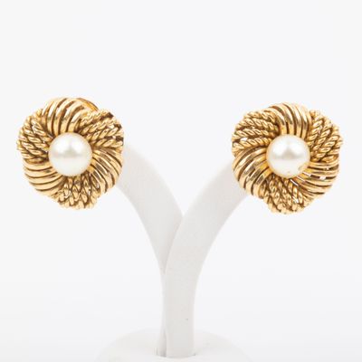 a pair of gold and pearl earrings on a white stand