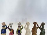 cinq figurines de couleurs et de tailles différentes sont alignées sur une surface blanche