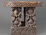 une petite table en bois dont le plateau est orné de sculptures
