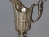 an antique silver plated pitcher on a pedestal with a handle