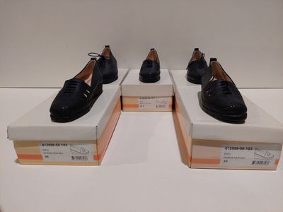 Trois paires de chaussures noires sont exposées dans une vitrine.
