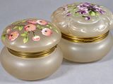 une paire de boîtes en verre ornées de fleurs peintes, posées sur une table