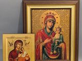 un tableau représentant une femme tenant un enfant dans ses bras, à côté d'une icône encadrée