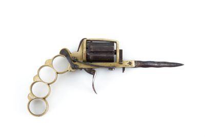un pistolet posé sur une surface blanche, à côté d'un poing américain