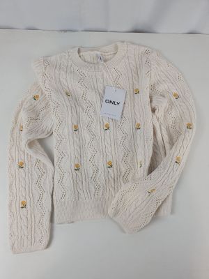 Le pull est blanc et orné de boutons dorés.