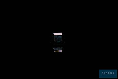 une petite fenêtre dans une pièce sombre où une lumière est allumée