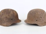 pair of wwii era german helmets with holes on the side