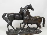 statue en bronze représentant deux chevaux au galop sur un sol rocheux