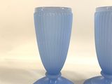 pair of blue glass vases sitting on top of a white table