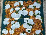 a close up of a green scarf with white flowers on it