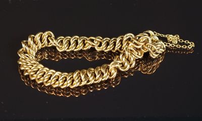gros plan d'un bracelet en chaîne en or sur une surface noire