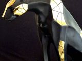 statue of a black and gold cat sitting on a black base
