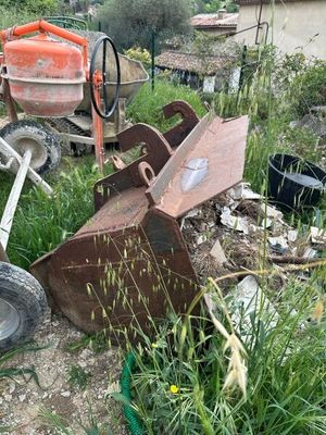 un tas de vieilleries dans la cour, à côté d'une bétonnière