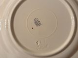 someone is holding a white plate with a red dot on it