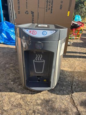 un distributeur d'eau posé par terre à côté d'une boîte