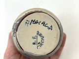 a hand holding a small vase with writing on it