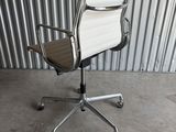 an office chair with a white leather seat sitting in front of a corrugated wall