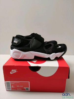 une paire de chaussures noires et blanches posée sur une boîte rouge