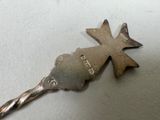 a silver spoon with a cross on it sitting on a table