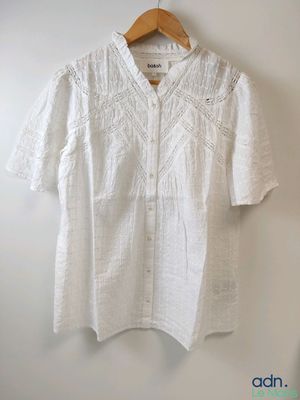 une chemise blanche accrochée au mur à côté d'un cintre en bois