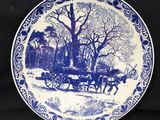 une image représentant une assiette bleue et blanche sur laquelle figure une calèche