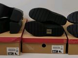 three pairs of black shoes sitting on top of boxes on a white surface