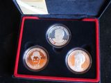 three coins in a red box with a picture of a man and a woman