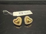 une paire de boucles d'oreilles en or en forme de cœur posées sur un fond noir