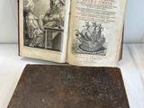 un vieux livre posé sur une table à côté d'un livre ouvert