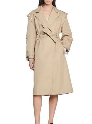a woman in a beige trench coat and black shoes