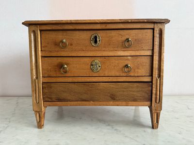 une petite commode en bois posée sur une table