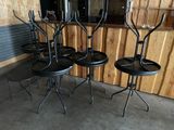 quatre tabourets en métal noir et une table dans une pièce aux murs en bois