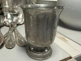a silver cup and spoons on a table