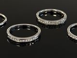 three silver rings with diamonds on a black surface