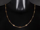 un collier à chaîne en or au motif raffiné, posé sur un mannequin