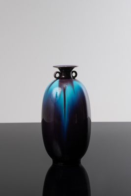 un vase bleu et noir posé sur une table noire