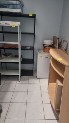 une pièce équipée d'un bureau, d'étagères et d'un réfrigérateur
