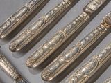 a lot of silver spoons and knives sitting on a table
