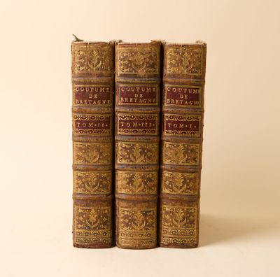 trois vieux livres posés l'un sur l'autre sur une surface blanche