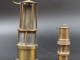pair of brass and glass lighthouse lamps on a black surface