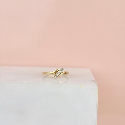 une bague en or sertie d'un diamant, posée sur un bloc de marbre blanc