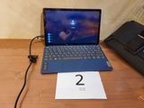 un ordinateur portable posé sur un bureau, à côté d'un bloc-notes