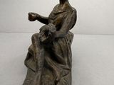 statue d'une femme assise sur un rocher, en train de lire un livre