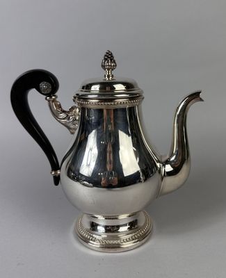 a silver teapot with a black handle on a white surface